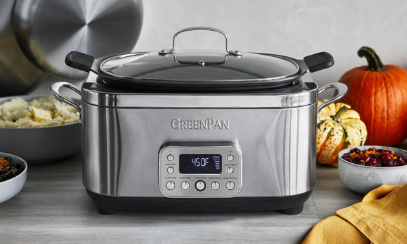 Stainless steel slow cooker surrounded by food and pumpkins