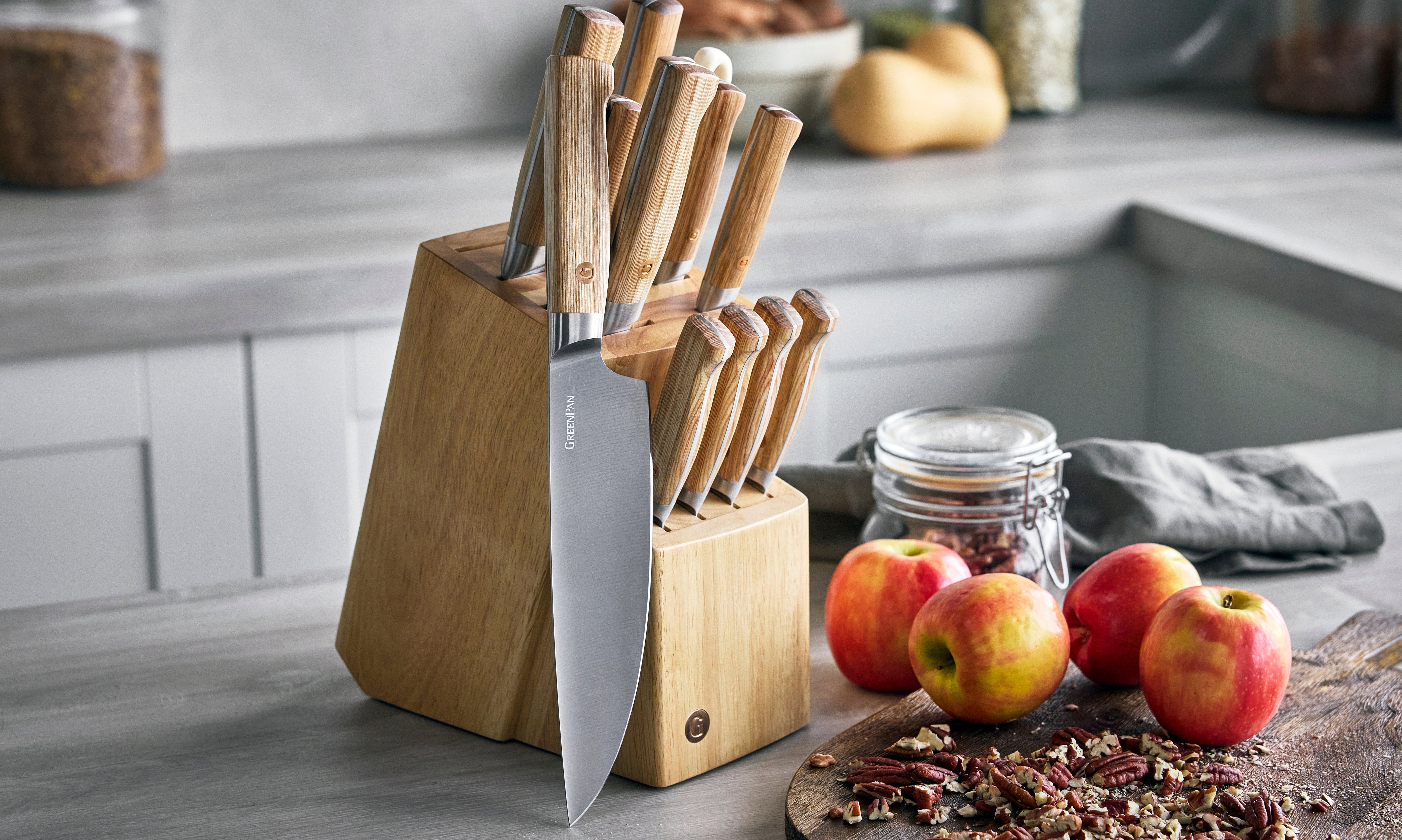 Wooden cutlery block beside apples and kitchen ingredients